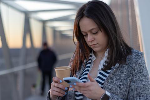 Woman outdoors on bridge looking at her mobile phone