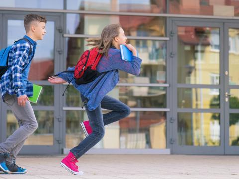 Children running from school with books in hand