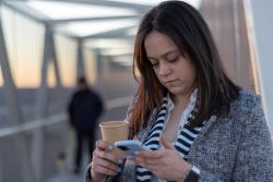 Woman outdoors on bridge looking at her mobile phone