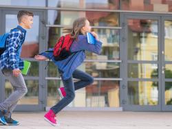 Children running from school with books in hand