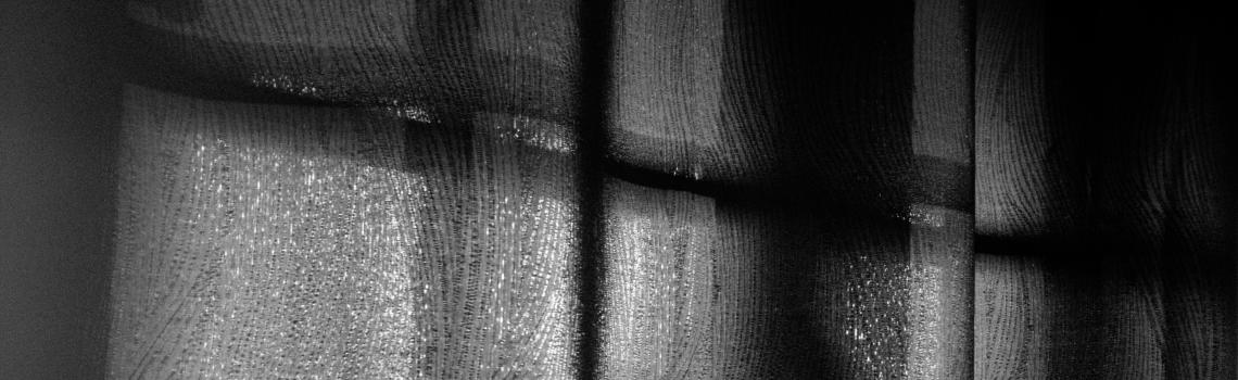 Looking out through darkened window curtains